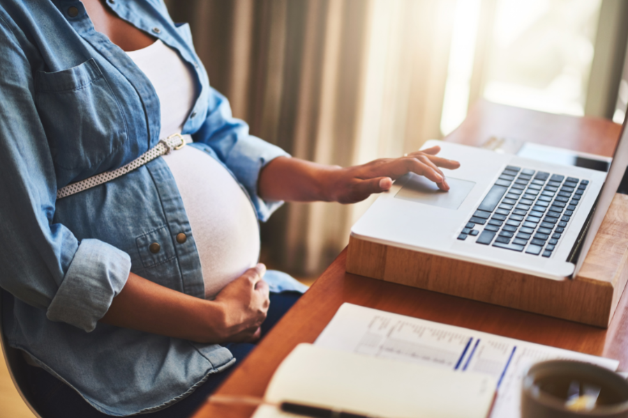 Schwangere Frau sitz am Schreibtisch © Getty Images/Canva