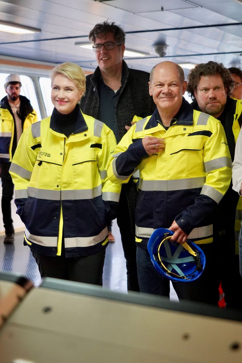 Bundeskanzler Olaf Scholz und Ministerpräsidentin Manuela Schwesig bei der Betriebsbesichtigung in gelber Schutzkleidung. Der Bundeskanzler hält einen Schutzhelm in der Hand.