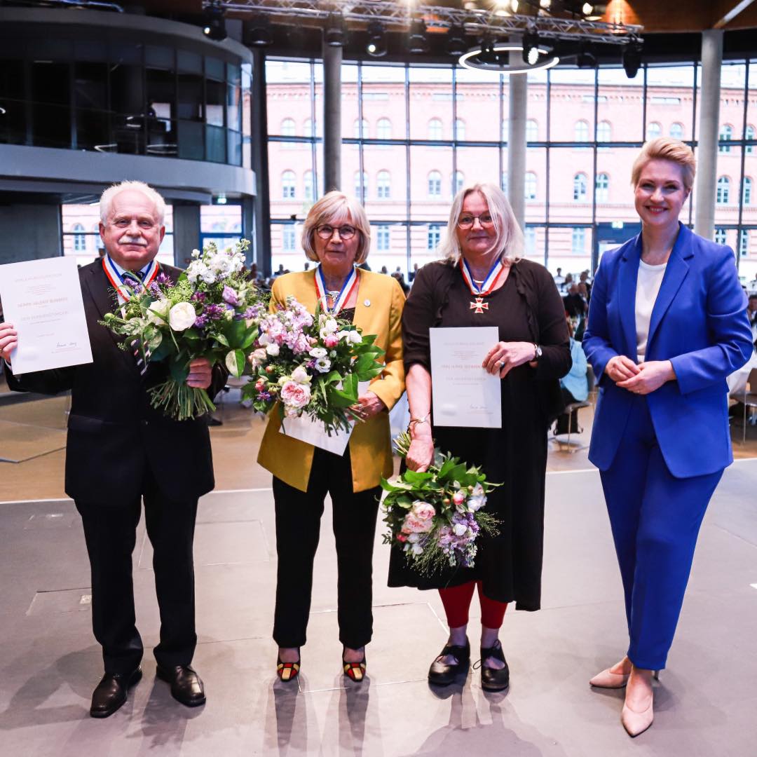 Ministerpräsidentin Manuela Schwesig mit Valeriiy Bunimov, Angelika Stiemer und Ulrike Seemann-Katz. Allen ist der Landesverdienstorden umgehängt und sie halten Blumensträuße in ihren Händen.
