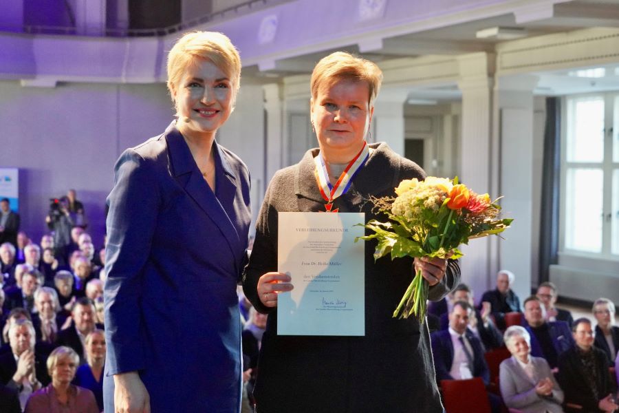 Ministerpräsidentin Manuela Schwesig mit Dr. Heike Müller, die einen Blumenstrauß und ihre Urkunde in den Händen hält.