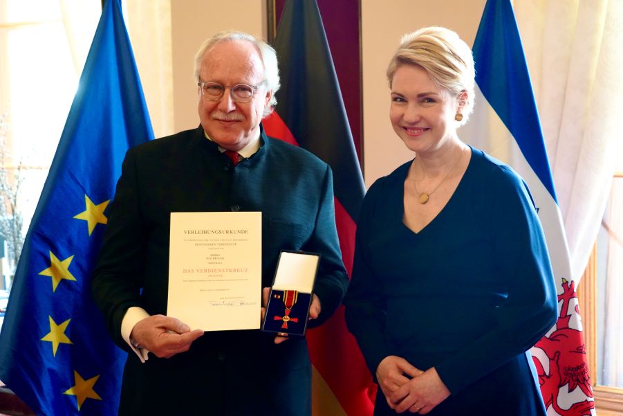Ministerpräsidentin Manuela Schwesig und Tilo Braune, der seine Urkunde und den Bundesverdienstorden, noch im Etui, hochhält.