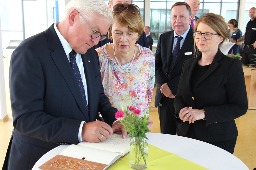 Bundespräsident Steinmeier und seine Gattin Elke Büdenbender tragen sich ins Gästebuch der JVA Neustrelitz ein. 