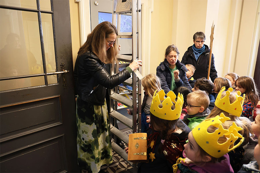 Die Kinder helfen der Ministerin, die Leiter im Eingangsbereich des Ministeriums aufzustellen. 