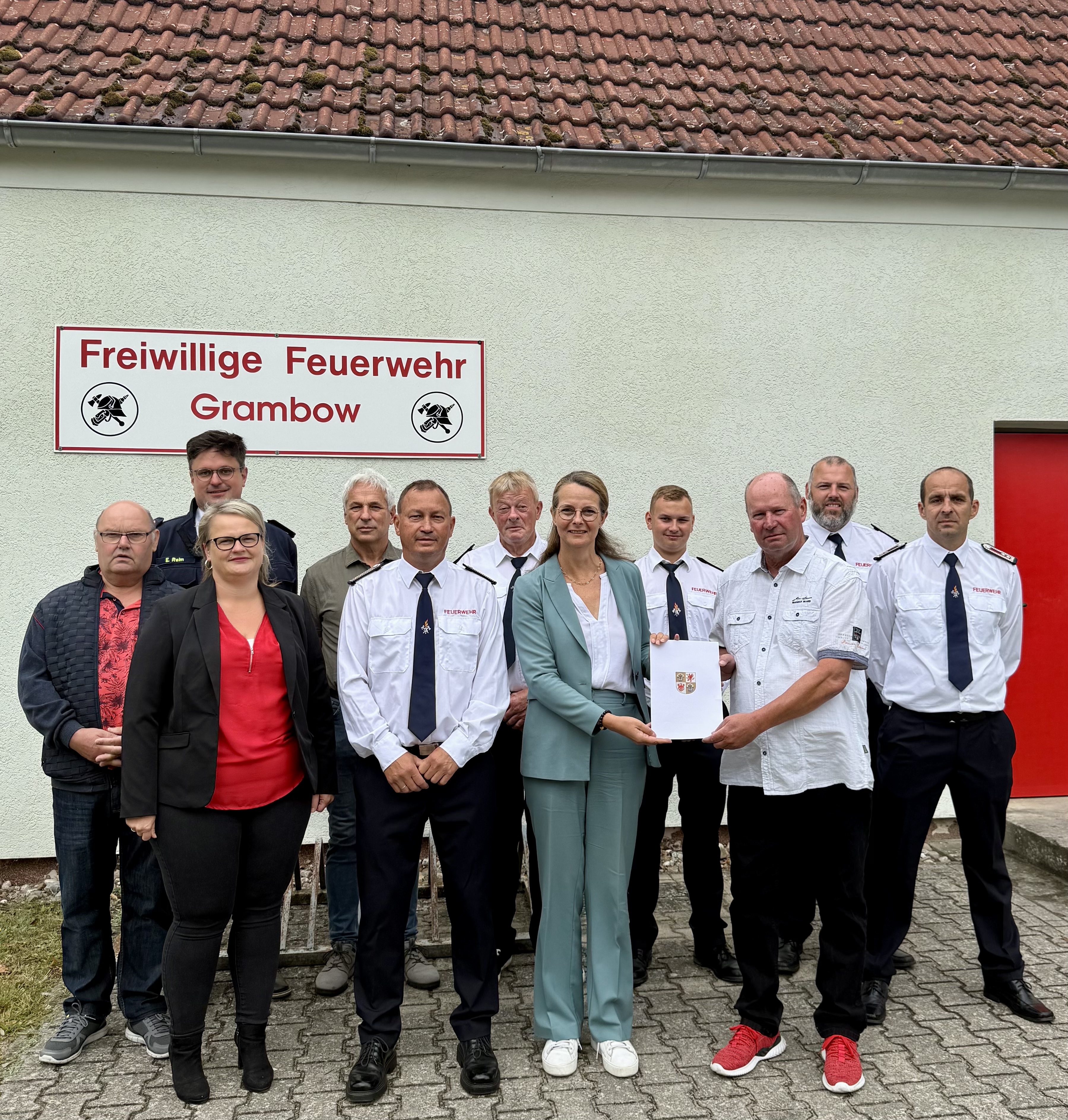 Ministerin Bettina Martin (Mitte) bei der Bescheidübergabe an den Bürgermeister der Gemeinde Mirko Ehmke, weiteren Gemeindevertretungen sowie Vertreterinnen und Vertreter der Freiwilligen Feuerwehr Grambow. Foto WKM MV