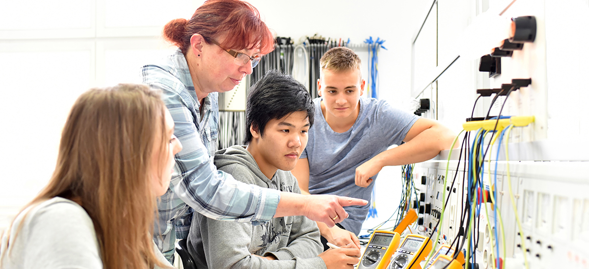Eine Lehrerin erklärt jungen Menschen Elektrotechnik, Foto: shutterstock
