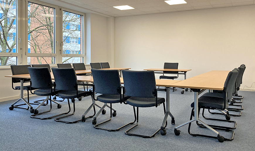 Blick in einen kleinen Beratungsraum, in dem die Tische und Stühle in U-Form angeordnet sind, Foto: KBS