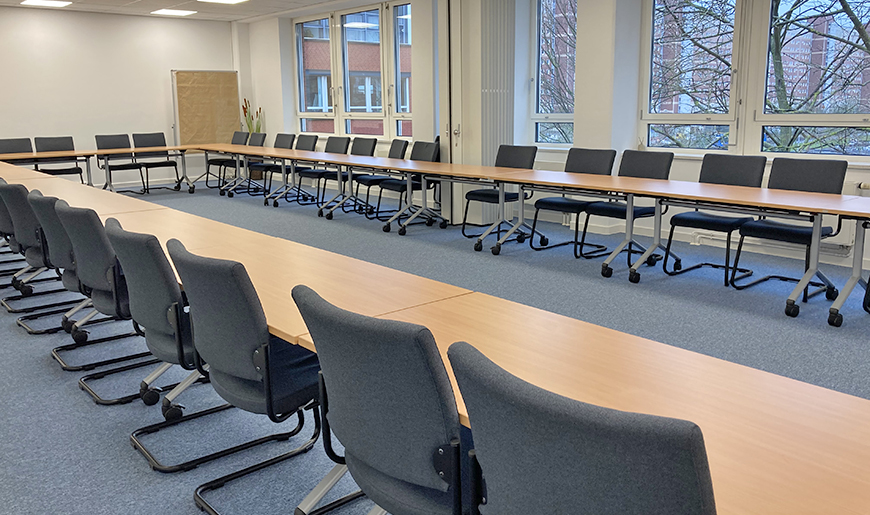 Blick in einem großen Beratungsraum, in dem die Tische und Stühle in O-Form angeordnet sind, Foto: KBS