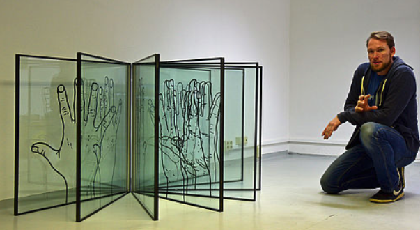 Künstler Tino Bittner hockt neben seinem Kunstwerk „Handumdrehen“