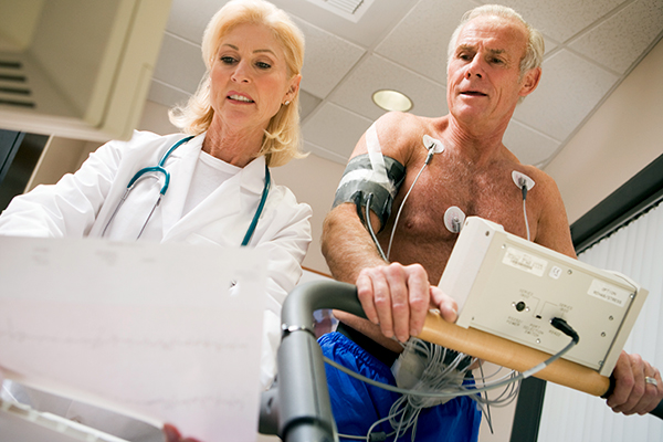 Ein Patient am Ergometer unter Aufsicht seiner Ärztin.