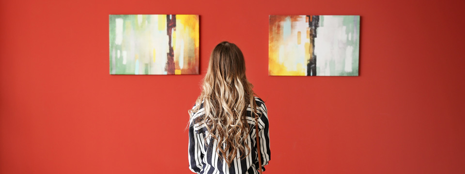 Eine Besucherin betrachtet Gemälde in einer Galerie. Foto: Pixel-Shot/ AdobeStock