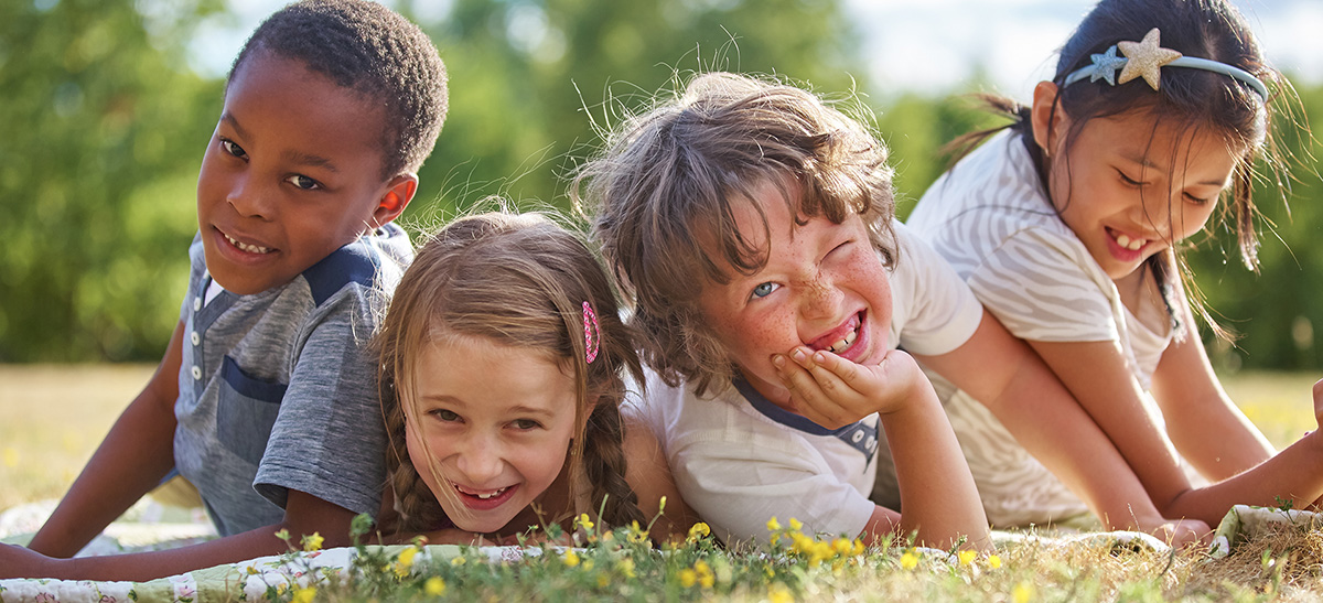 Vier Kinder liegen auf einer Wiese, Foto: shutterstock/Robert Kneschkeübergang