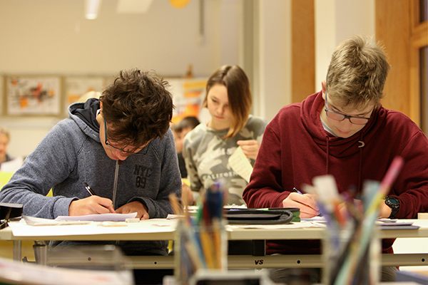 Zwei Schüler sitzen am Tisch und schreiben in ihre Hefte, Foto: Silke Winkler