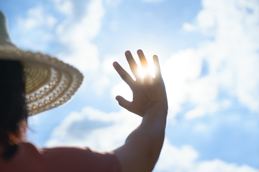 Eine Frau, die ihre Hand der hellen Sonne entgegenstreckt