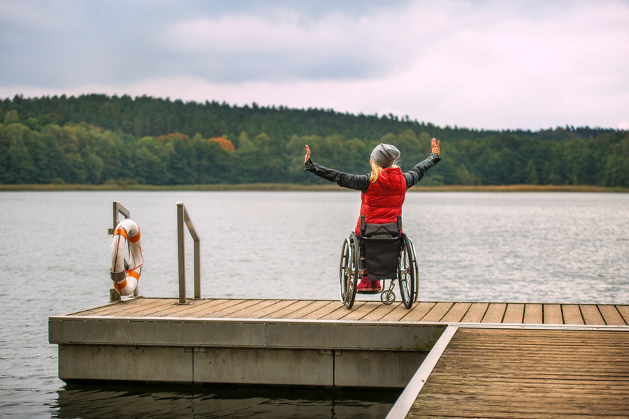 Frau im Rollstuhl auf einem Steg am See