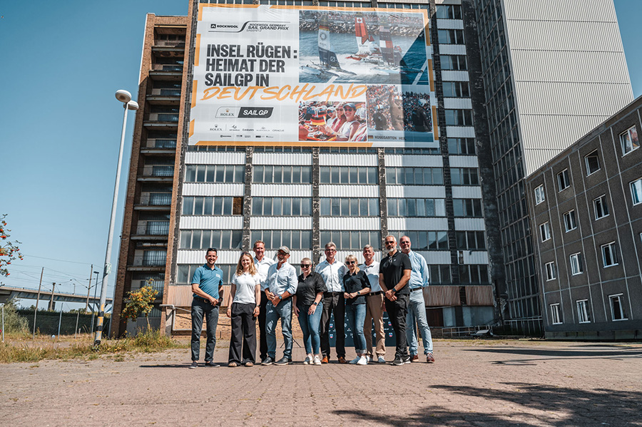 Im Beisein von Wirtschaftsminister Dr. Wolfgang Blank (4.v.l.) wurde am 30.07.2026 das große Werbeplakat am Werfhochhaus in Stralsund enthüllt. Das riesige Banner in Nähe der Rügenbrücke wirbt für die SailGP in Sassnitz vom 22. und 23. August 2026.