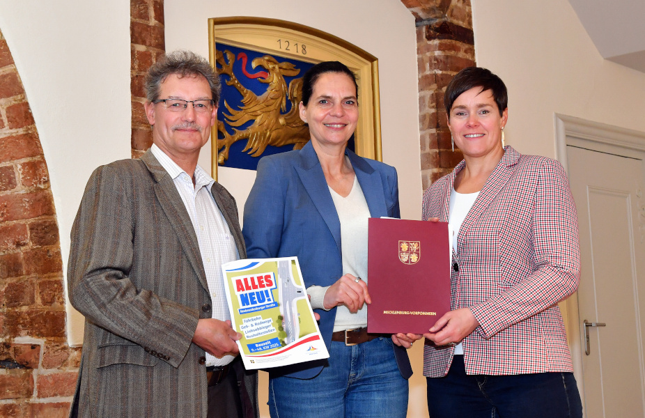 Am 08.04.2025 hat Wirtschaftsstaatsekretärin Ines Jesse (M.) einen Zuwendungsbescheid an Rostocks Oberbürgermeisterin Eva-Maria Kröger und den Leiter des Rostocker Tiefbauamtes Heiko Tiburtius überreicht. Gefördert wird der Um- und Ausbau der Neubrandenburger Straße südlich des Bahn­übergangs.