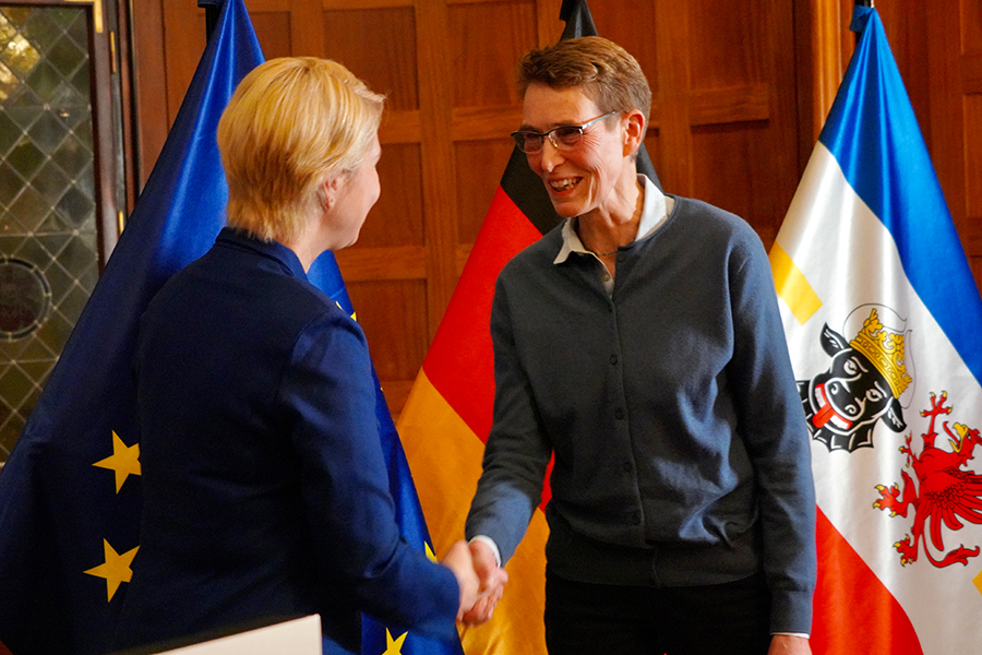 Ministerpräsidentin Manuela Schwesig gratuliert Barbara Niehaus zu ihrer Auszeichnung. Im Hintergrund sind die EU-, die Deutschland- und die Mecklenburg-Vorpommern-Flagge zu sehen.