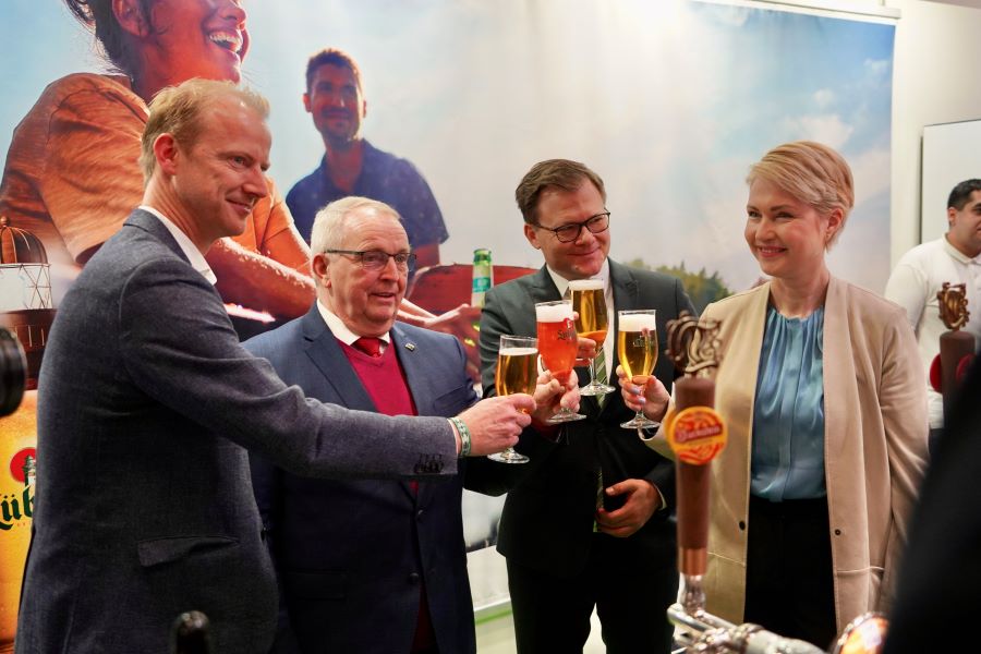 Bei der Lübzer Brauerei: Geschäftsführer Bastian Pochstein mit Ministerpräsidentin Manuela Schwesig, Staatsminister Carsten Schneider sowie Minister Dr. Till Backhaus. Alle halten Biergläser hoch.