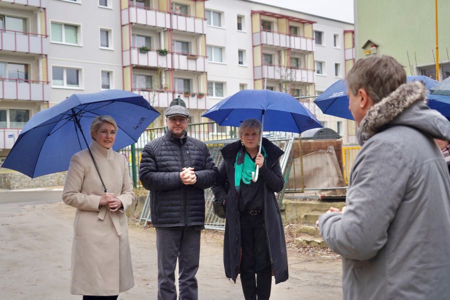 Besuch des neu entstehenden Schulcampus in Anklam mit Bürgermeister Michael Galander inmitten von Ministerpräsidentin Manuela Schwesig und der Ministerin für Bildung und Kindertagesförderung Simone Oldenburg. Die beiden Damen tragen aufgespannte Regenschirme.. 