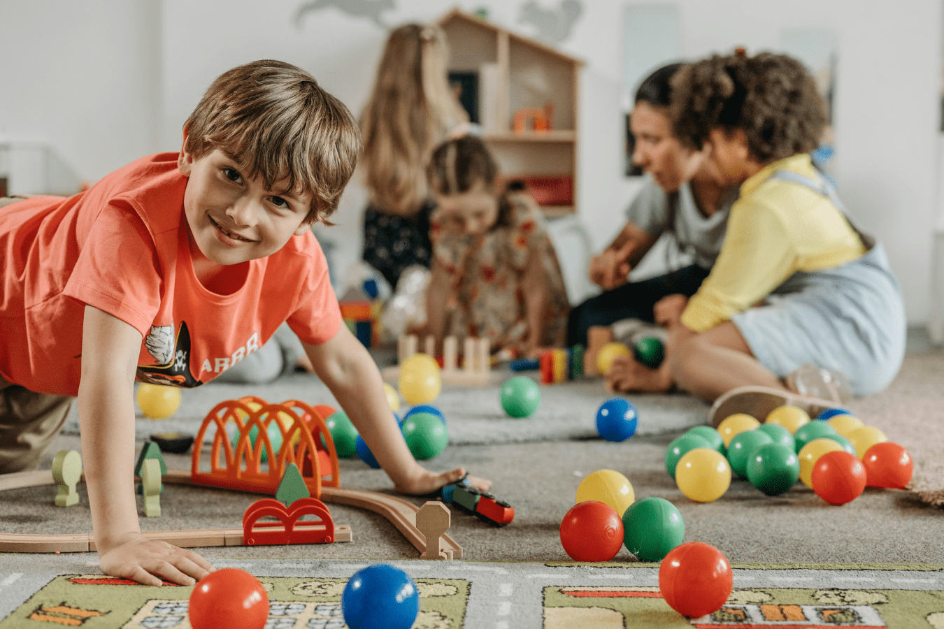 Spielende Kinder in einem Kindergarten. Auf dem Boden liegt Spielzeug.