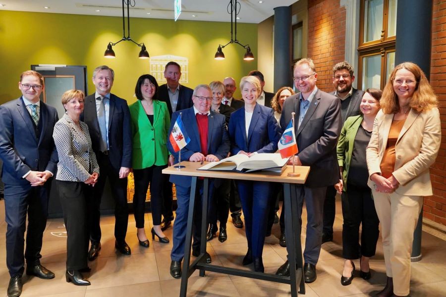 Auf einem Tisch liegt das Gästebuch der Hansestadt Anklam. Daneben stehen die Flaggen Anklams und Mecklenburg-Vorpommerns. Hinter dem Tisch stehen Ministerpräsidentin Manuela Schwesig und Anklams Bürgermeister Michael Galander und um den Tisch herum die anderen Mitglieder des Landeskabinetts. © StK M-V Auf einem Tisch liegt das Gästebuch der Hansestadt Anklam. Daneben stehen die Flaggen Anklams und Mecklenburg-Vorpommerns. Hinter dem Tisch stehen Ministerpräsidentin Manuela Schwesig und Anklams Bürgermeister Michael Galander und um den Tisch herum die anderen Mitglieder des Landeskabinetts.