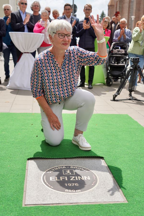 Auf einem Knie und winkend hinter der Bronzeplatte, die für sie im "Walk of Sport" verlegt wurde: Elfi Zinn