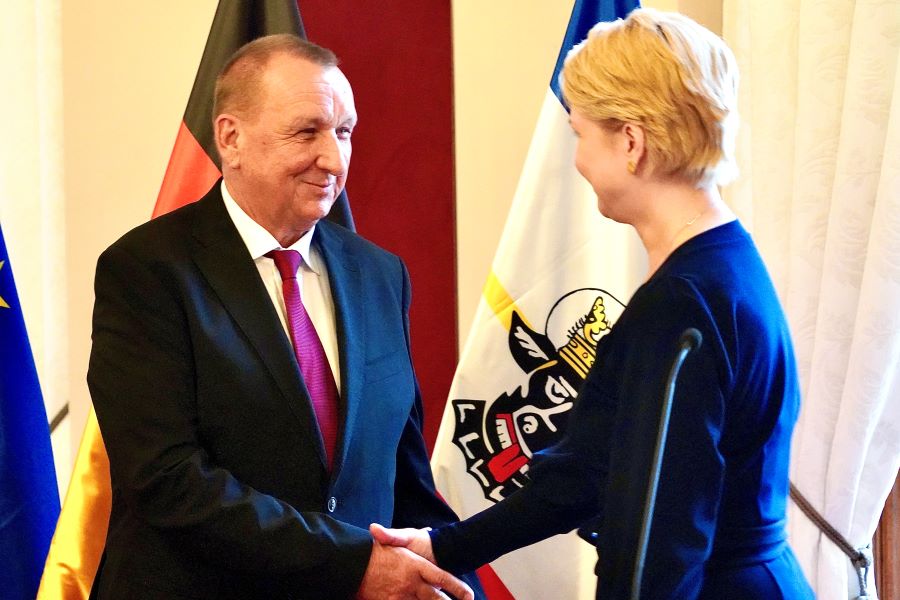 Die Ministerpräsidentin gratuliert Gerold Jürgens. Im Hintergrund sind die Deutschland- und die Mecklenburg-Vorpommern-Flagge zu sehen.