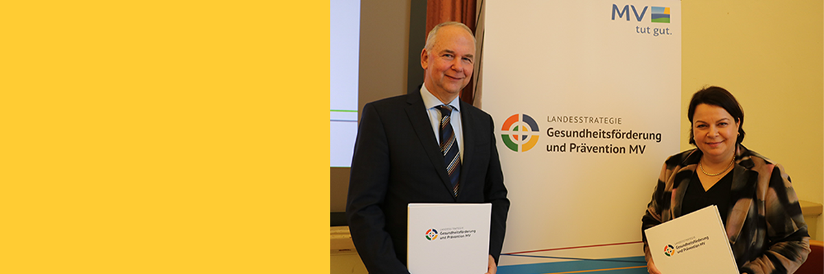 Der Co-Vorsitzende der Gesundheitskommission MV Professor Dr. Steffen Fleßa mit der Ministerin für Soziales, Gesundheit und Sport Stefanie Drese vor dem Logo zur Landesstrategie Gesundheitsförderung und Prävention MV.