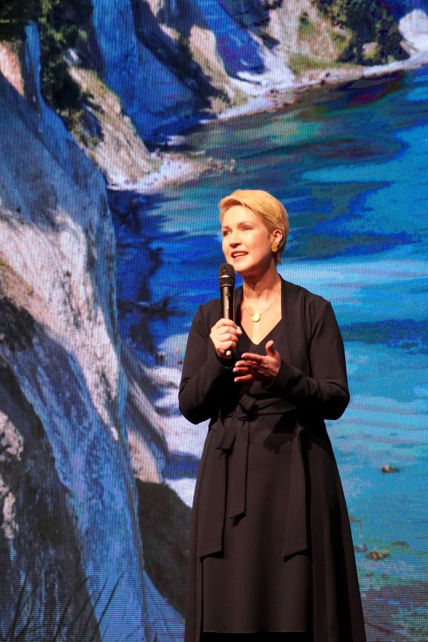 Ministerpräsidentin Manuela Schwesig, mit einem Mikrophon in der Hand, ans Publikum gewandt. Im Hintergrund sind die Rügener Kreidefelsen zu erkennen.