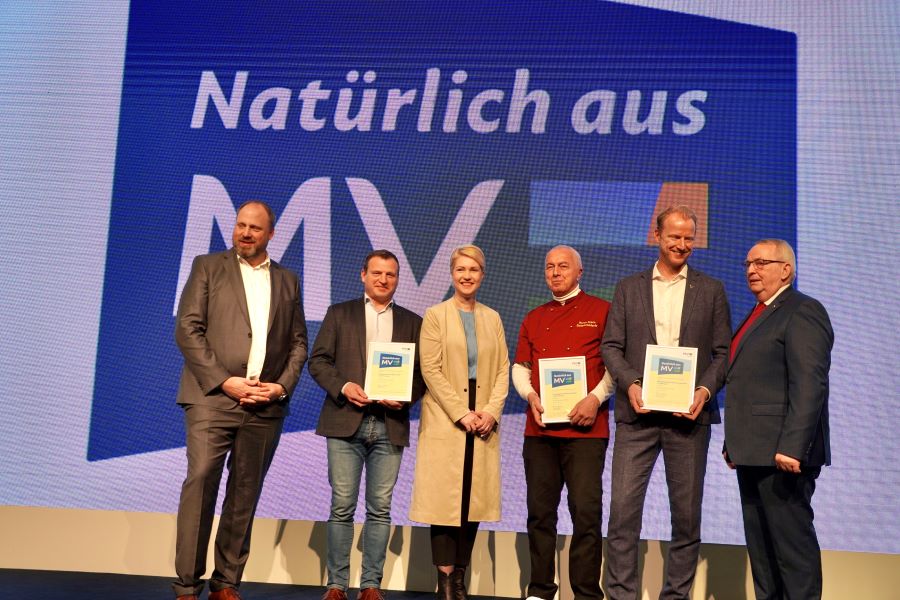 Gruppenbild, mit dem neuen Regionalzeichen "Natürlich aus MV" im Hintergrund, mit Ministerpräsidentin Manuela Schwesig, Minister Dr. Till Backhaus, dem Vorsitzendes der AMV-Marketinggesellschaft Tobias Blömer sowie, ihre Urkunden haltend, den Geschäftsführern Armin Kremer (Mecklenburger Landpute), Ulrich Deprie (Schokoladerie Juillet de Prie) und Bastian Pochstein (Mecklenburgische Brauerei Lübz). © StK M-V Gruppenbild, mit dem neuen Regionalzeichen "Natürlich aus MV" im Hintergrund, mit Ministerpräsidentin Manuela Schwesig, Minister Dr. Till Backhaus, dem Vorsitzendes der AMV-Marketinggesellschaft Tobias Blömer sowie, ihre Urkunden haltend, den Geschäftsführern Armin Kremer (Mecklenburger Landpute), Ulrich Deprie (Schokoladerie Juillet de Prie) und Bastian Pochstein (Mecklenburgische Brauerei Lübz).
