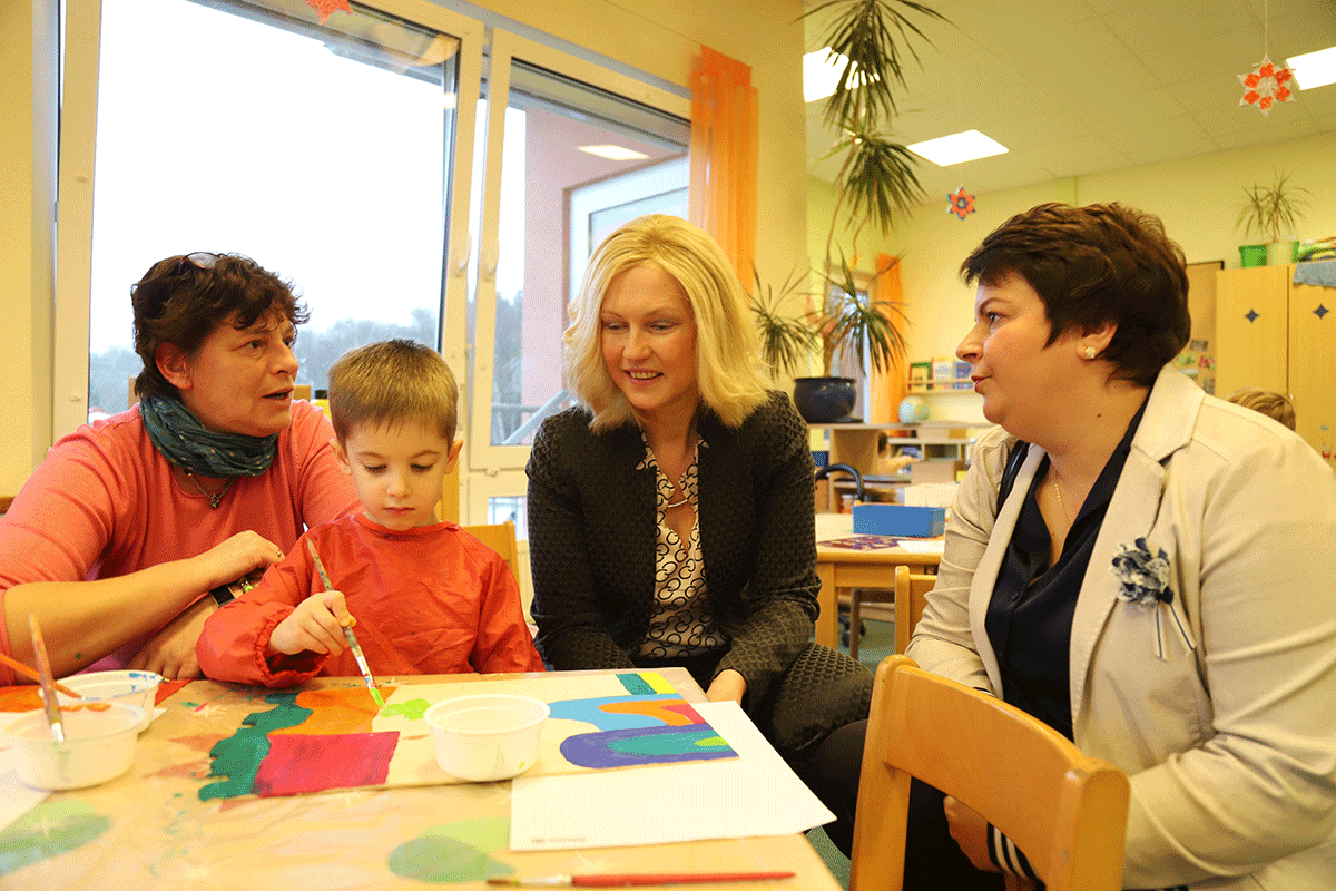 Ministerpräsidentin Manuela Schwesig und Sozialministerin Stefanie Drese am Tisch im Gespräch mit einer Erzieherin und einem Jungen, der malt