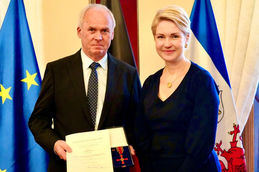 Die Ministerpräsidentin mit Joachim Masuch. Im Hintergrund ist die Deutschland- und die Mecklenburg-Vorpommern-Flagge zu erkennen.