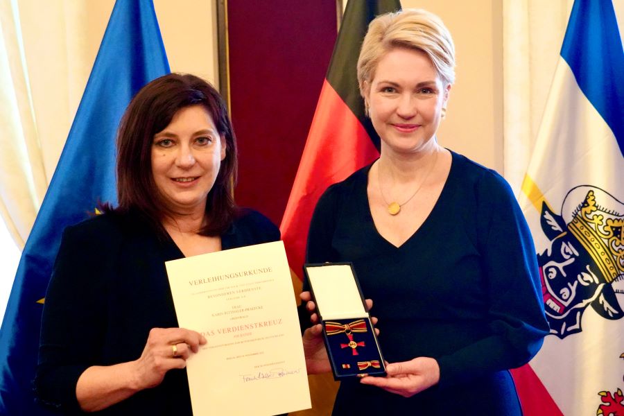Die Ministerpräsidentin mit Karin Ritthaler-Praefke, die ihre Urkunde hochhält. Die Ministerpräsidentin hält den Bundesverdienstorden in die Kamera. © StK M-V Die Ministerpräsidentin mit Karin Ritthaler-Praefke, die ihre Urkunde hochhält. Die Ministerpräsidentin hält den Bundesverdienstorden in die Kamera.