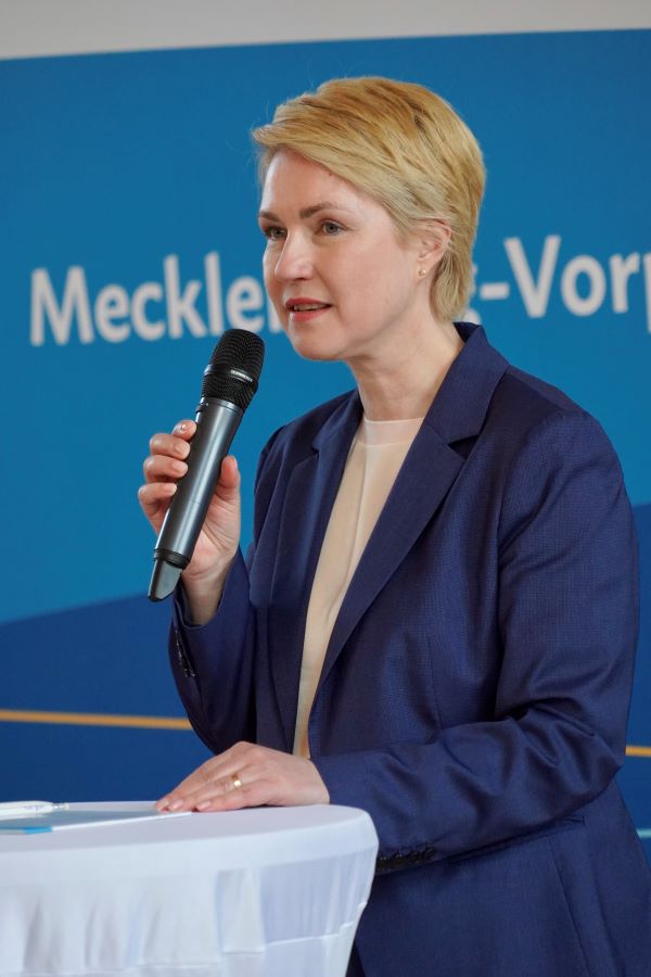 Ministerpräsidentin Manuela Schwesig am Stehtisch mit Mikrophon in der Hand.