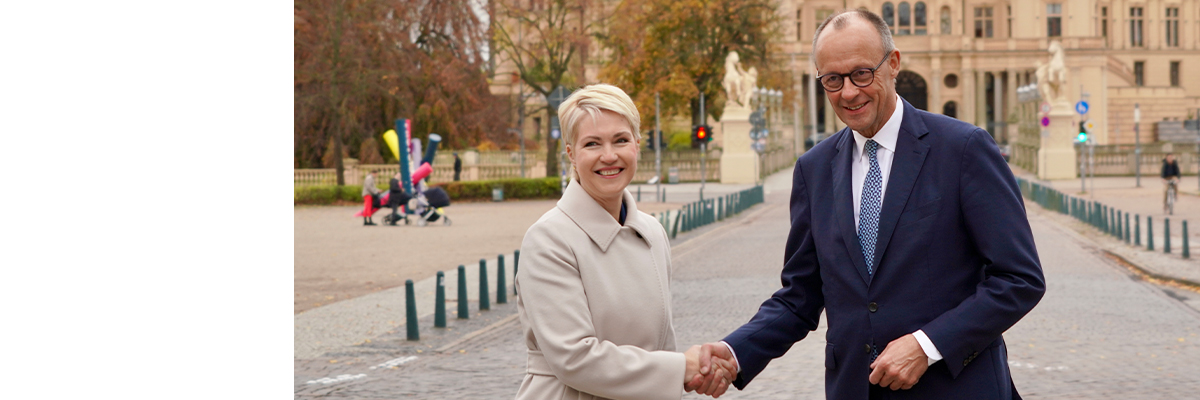 Bundeskanzler Friedrich Merz und Ministerpräsidentin Manuela Schwesig beim Handschlag. Im Hintergrund ist das Schweriner Schloss zu sehen.