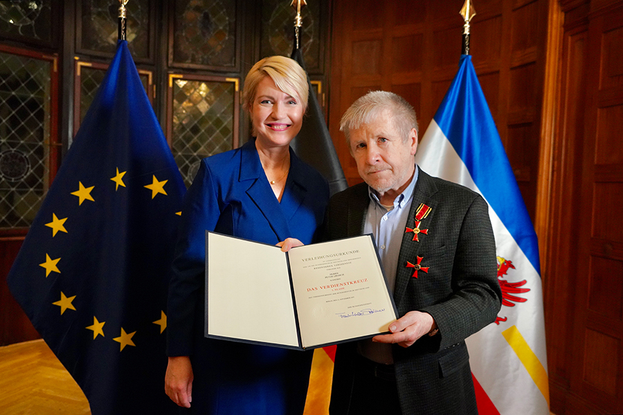 Peter Grosch und Ministerpräsidentin Manuela Schwesig halten zusammen die Verleihungsurkund in die Kamera