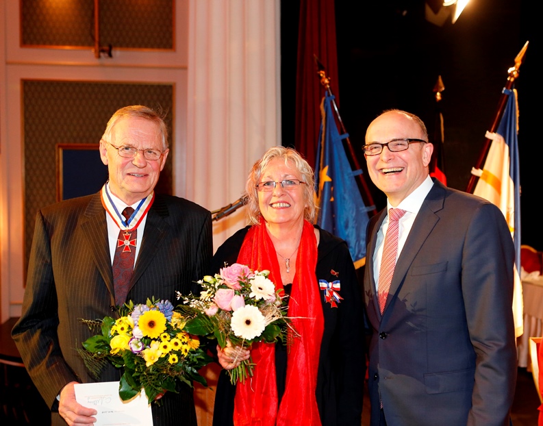 Der damalige Ministerpräsident Erwin Sellering mit Gerd-Heinrich Kröchert und Marion Richter. Beide tragen ihre Orden und halten ihren Blumenstrauß in die Kamera.