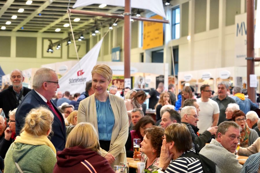 Schwesig und Dr. Backhaus im Gespräch mit Gästen. Um sie herum sind viele weitere Gäste, sitzend und stehend, zu sehen.