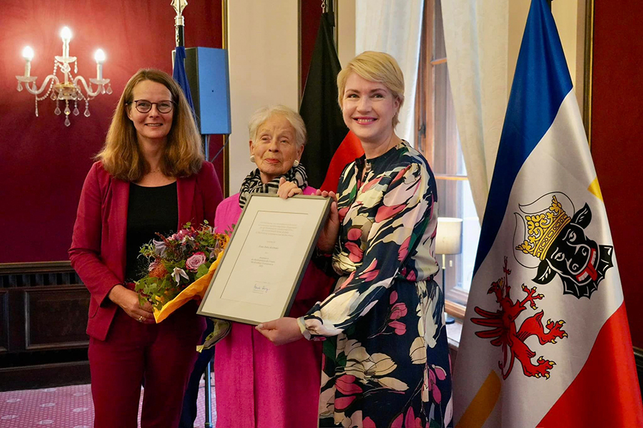 Ministerpräsidentin Manuela Schwesig und Ministerin Bettina Martin mit der Trägerin des Landeskulturpreises 2023 Anka Kröhnke, die einen Blumenstrauß in der Hand hält. Gemeinsam mit der Ministerpräsidentin hält sie die Urkunde hoch. 