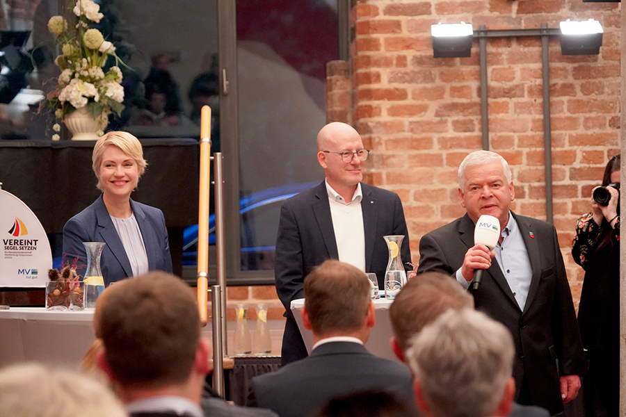 Ministerpräsidentin Manuela Schwesig mit mit Zarrentins Bürgermeister Klaus Draeger und Moderator Peter Kranz Alle befinden sich an Stehtischen und blicken ins Publikum. Der Bürgermeister hält ein Mikrophon.