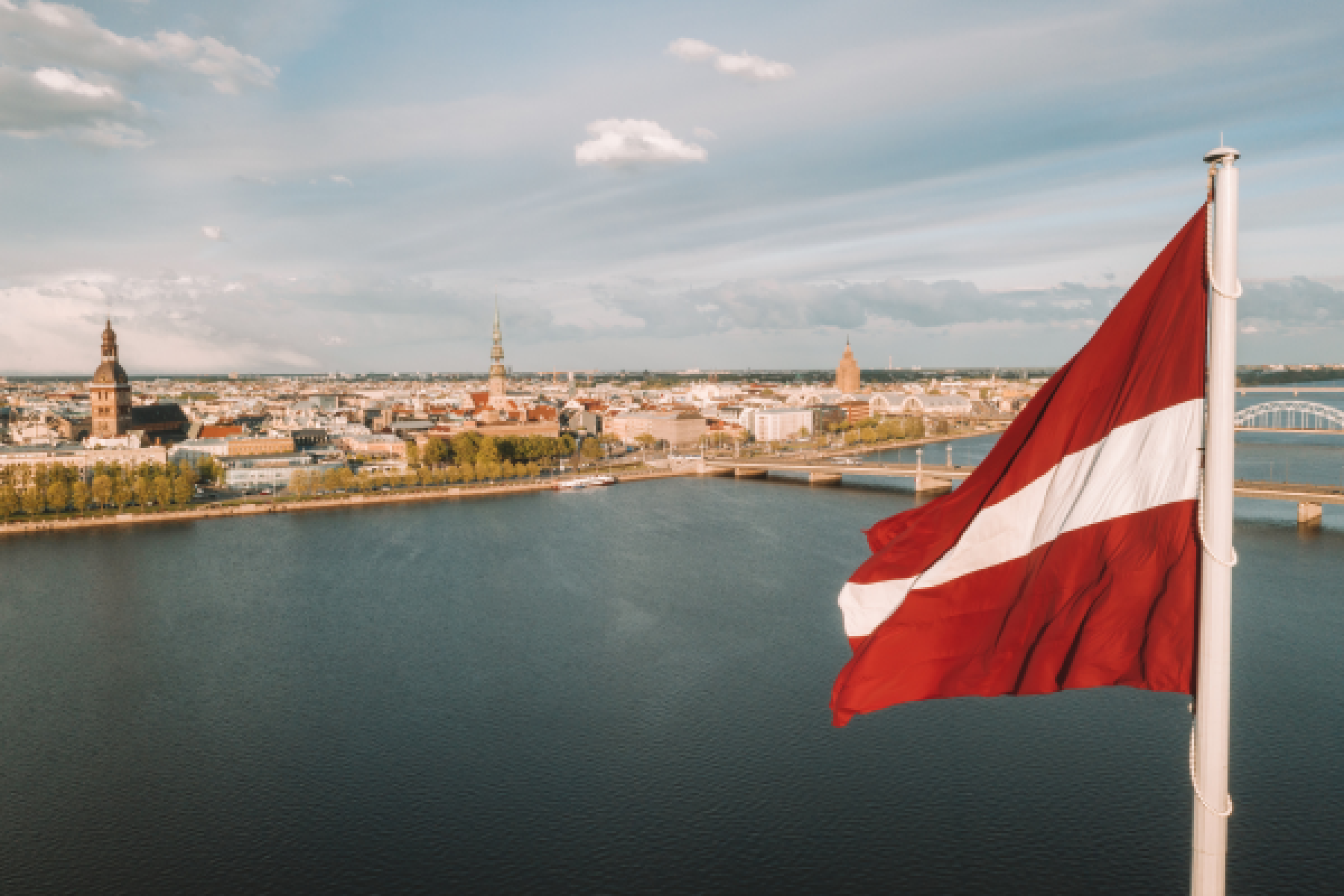 Panorama der Stadt Riga mit einer lettischen Flagge im Vordergrund  © Canva